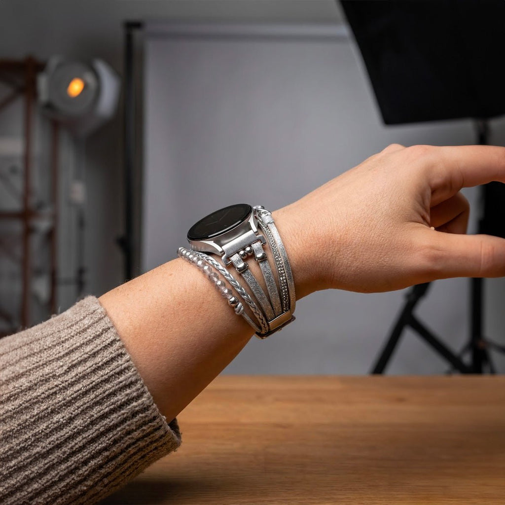 Bracelet montre multi-rangs gris simili cuir vegan avec perles argentées et motif infini sur poignet féminin.