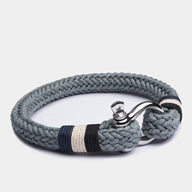 Bracelet homme tressé gris en coton avec fermoir mousqueton en acier inoxydable et détails bleus et blancs.