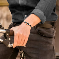 Bracelet homme noir en cuir avec mousqueton en acier inoxydable porté au poignet.