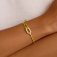 Bracelet ajustable en nylon jaune avec mousqueton en acier inoxydable sur peau bronzée.