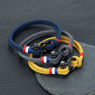 Bracelet mousqueton en nylon tressé bleu marine, gris et jaune avec fil ciré bleu, blanc, rouge et fermoir acier inoxydable.