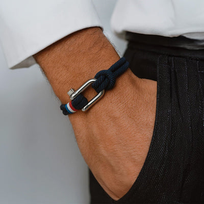 Bracelet en corde bleu marine avec fermoir mousqueton en métal argenté et détail tricolore rouge blanc bleu.