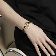 Bracelet homme en cuir tressé noir avec mousqueton et pendentif en acier doré.