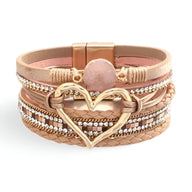 Bracelet multi-rangs beige avec grand cœur doré central et perle rose, détails brillants et texture cuir.