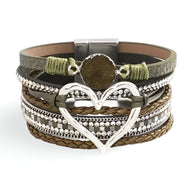 Bracelet multi-rangs vert kaki avec grand cœur argenté central et détails tressés et perles métalliques.