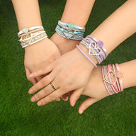 Bracelets multi-rangs en cuir, grand cœur central en métal, avec perles colorées, tons beige, turquoise, rose pâle.