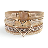 Bracelet multi-rangs beige avec grand cœur métallique doré et pierre centrale ronde rose pâle.