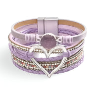 Bracelet multi-rangs violet clair avec grand cœur central en métal argenté et perles décoratives.