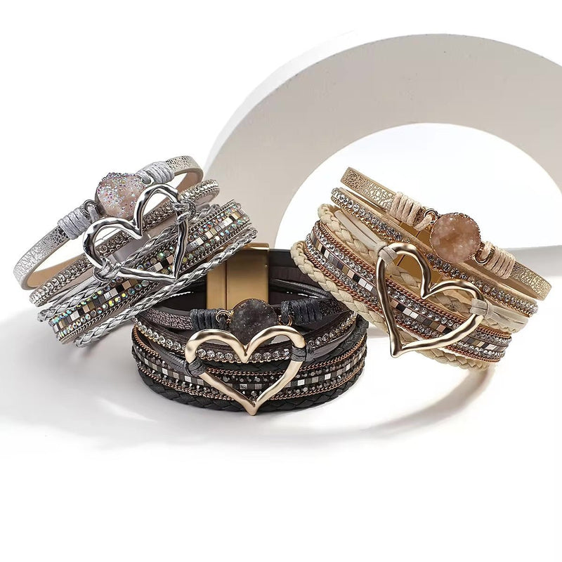 Trois bracelets multi-rangs pour femme en noir, beige et blanc avec grand cœur central métallisé.