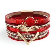 Bracelet multi-rangs rouge avec grand cœur central métallique doré et strass scintillants.
