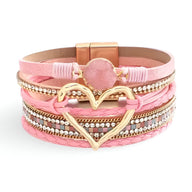 Bracelet multi-rangs rose avec grand cœur central doré et perle rose pâle.