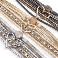 Bracelet multi-rangs beige avec cœur central doré et pierre centrale beige scintillante.