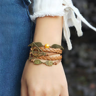 Bracelet multi-rangs en cuir marron avec breloques ailes d'ange et hiboux en métal doré, perle jaune, style bohème.