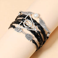 Bracelet multi-rangs marron en cuir tressé avec pendentifs métal ailes d'ange, hiboux et perle blanche.