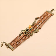 Bracelet multi-rangs marron en cuir tressé avec pendentifs ailes d'ange et hiboux en métal doré.