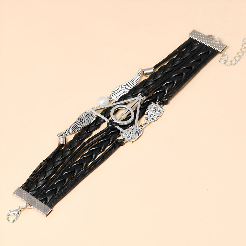 Bracelet multi-rangs noir en cuir tressé avec breloques ailes d'ange, hibou et symbole géométrique argentés.