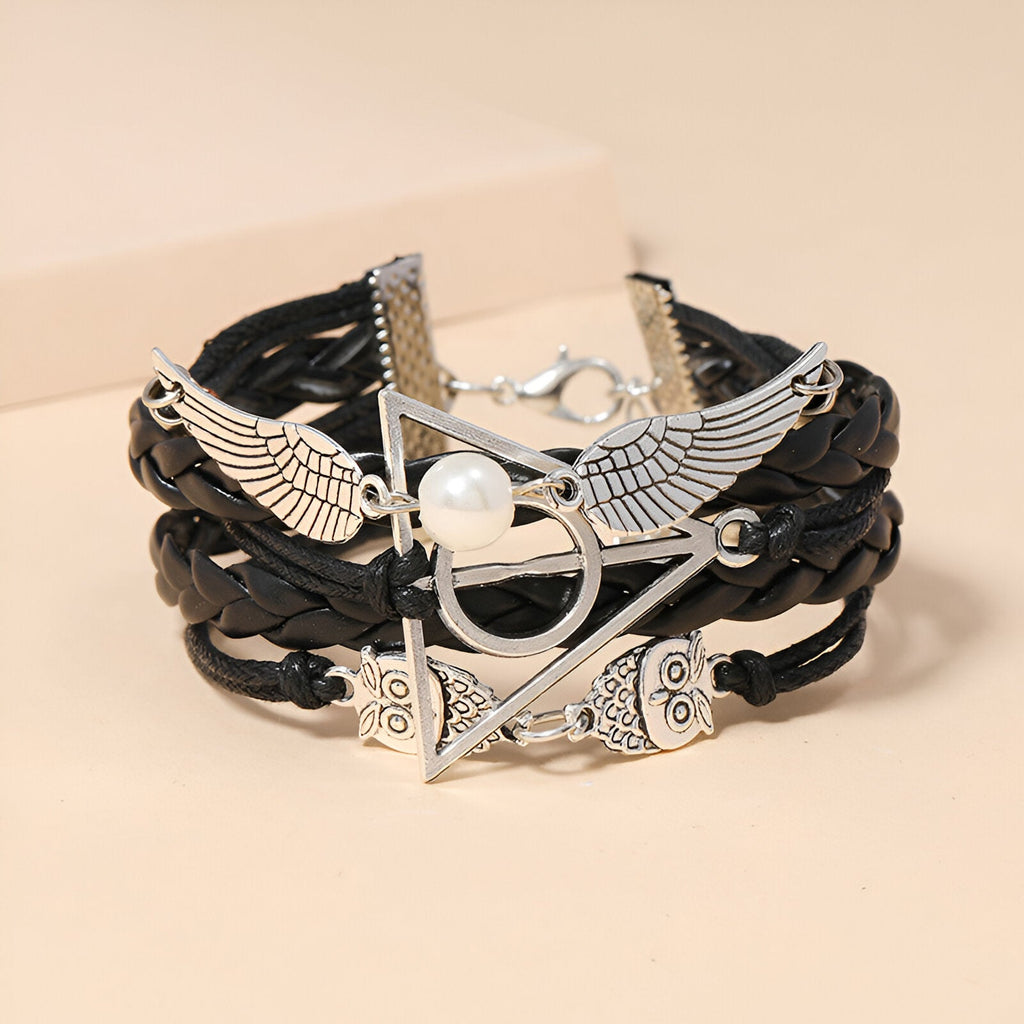 Bracelet multi-rangs en cuir noir avec ailes d'ange, hiboux en métal argenté et perle blanche centrale.
