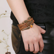 Bracelet multi-rangs marron en cuir tressé avec pendentifs ailes d'ange et hiboux en métal bronze.