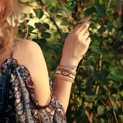 Bracelet multi-rangs beige orné de perles fines porté sur un poignet féminin en extérieur lumineux.