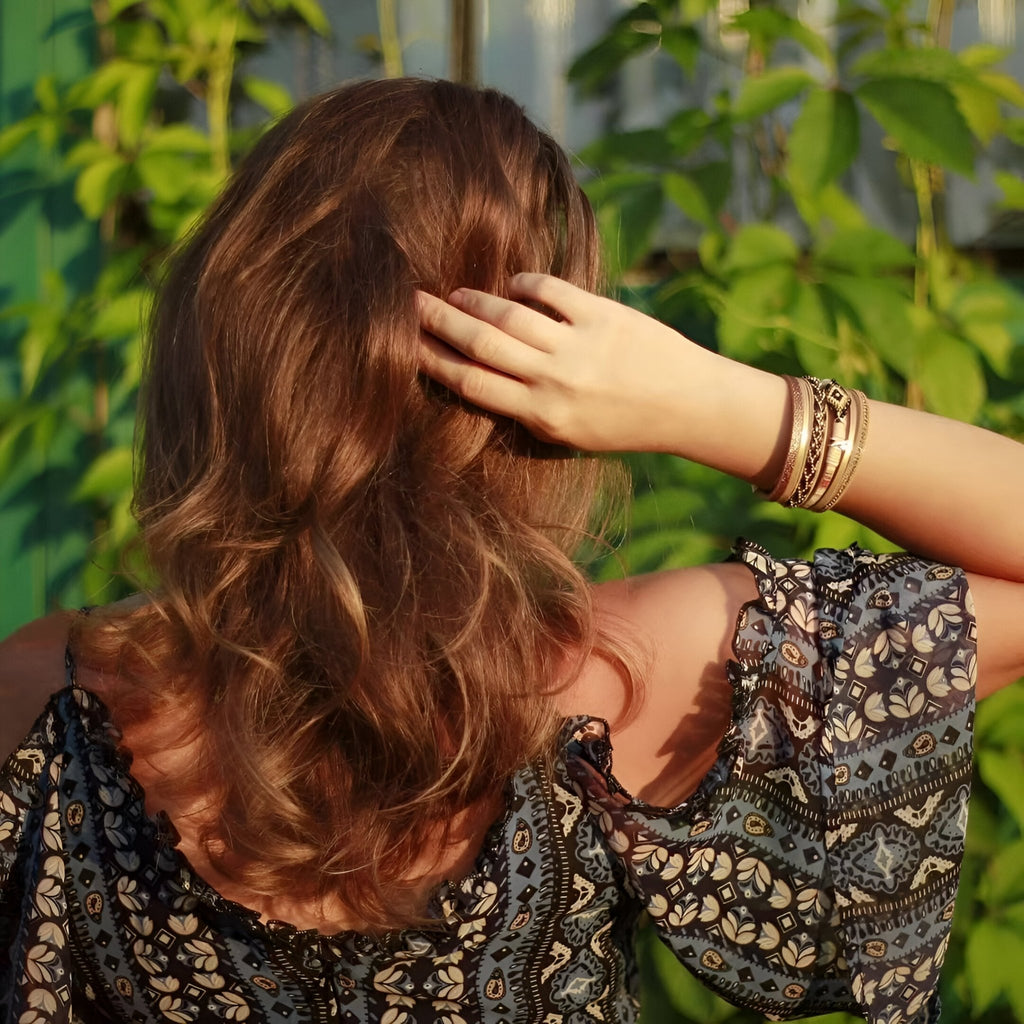 Bracelet multi-rangs beige perlé porté au poignet, style boho chic, avec plusieurs fines chaînes et perles délicates.