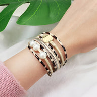 Bracelet multi-rangs léopard marron orné de perles blanches et détail doré, porté au poignet.