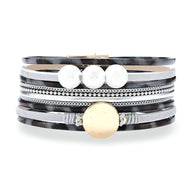 Bracelet multi-rangs léopard marron et noir avec perles blanches et médaille dorée brillante.