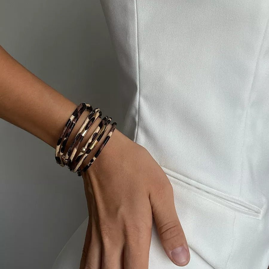 Bracelet multi-rangs en cuir beige à motif léopard stylisé, porté au poignet femme.