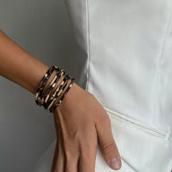 Bracelet multi-rangs en cuir beige à motif léopard stylisé, porté au poignet femme.