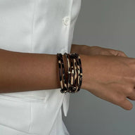 Bracelet multi-rangs léopard beige et noir porté au poignet, style féminin élégant.
