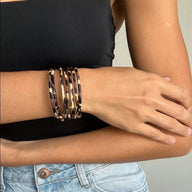 Bracelet multi-rangs femme style léopard beige et noir avec détails dorés porté au poignet.