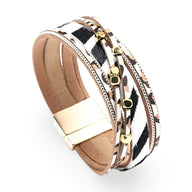 Bracelet multi-rangs en cuir beige avec imprimé léopard noir et blanc, détails dorés et fermeture magnétique.