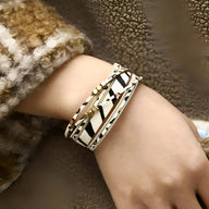 Bracelet multi-rangs pour femme avec motifs léopard noir et blanc, détails dorés et perles blanches.