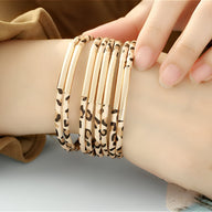 Bracelet multi-rangs beige avec motif léopard, fines barres dorées, style Savana élégant.