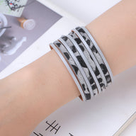 Bracelet multi-rangs gris à motif léopard noir sur cuir, style moderne et élégant pour femme.