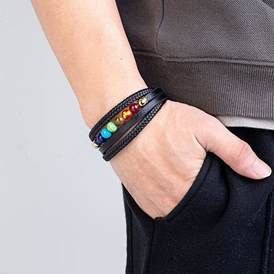 Bracelet multi-rangs en cuir noir avec perles colorées représentant les 7 chakras, porté homme.
