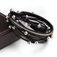 Bracelet multi-rangs noir avec breloques argentées rondes et fines chaînes brillantes.