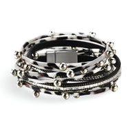 Bracelet multi-rangs noir et blanc avec breloques argentées et fermeture magnétique carrée.