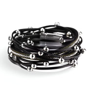 Bracelet multi-rangs noir avec breloques sphériques argentées et chaîne fine torsadée.