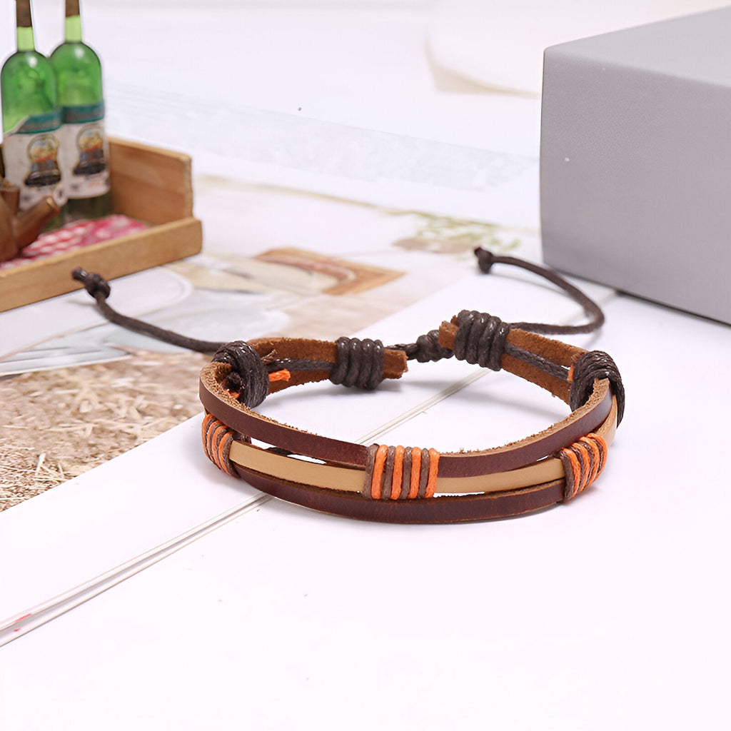 Bracelet multi-rangs en cuir marron avec détails orange et fermoir coulissant réglable.