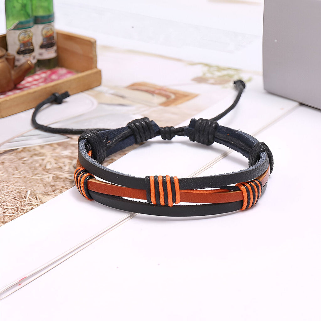 Bracelet multi-rangs en cuir noir et marron avec détails orange, style mixte, fermeture ajustable.