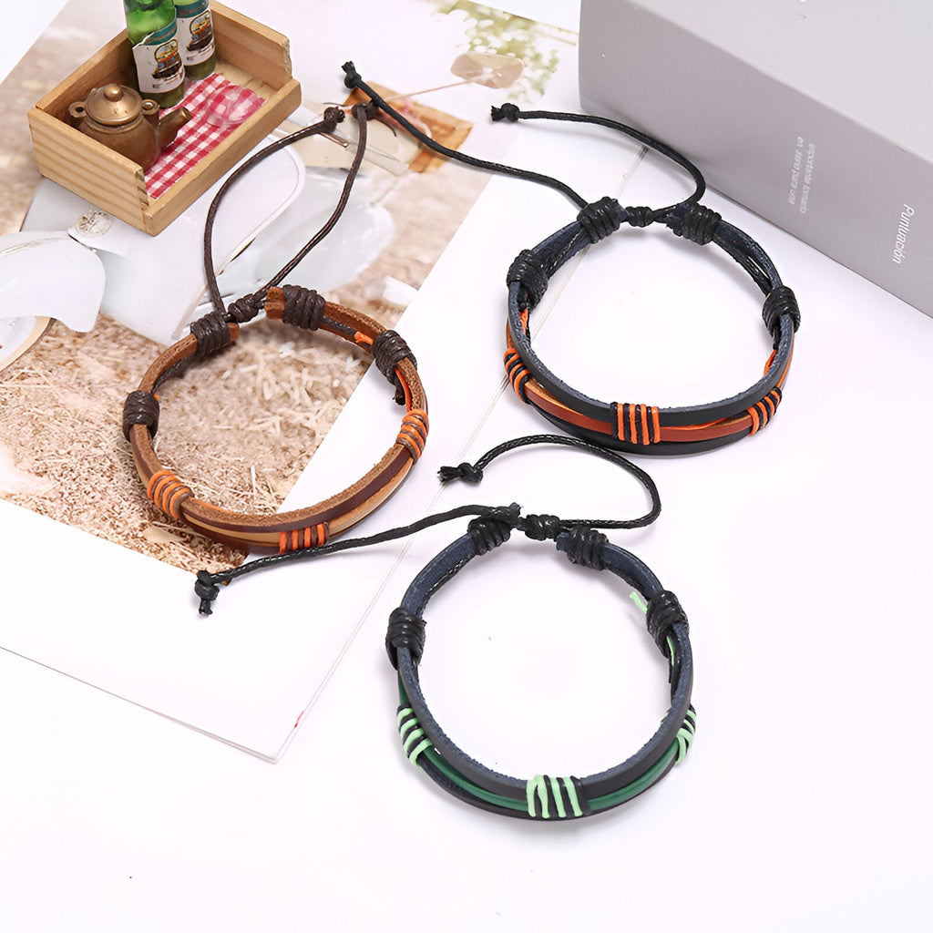 Trois bracelets multi-rangs en cuir bi-colore, styles noir-marron, noir-vert et marron avec détails tissés colorés.
