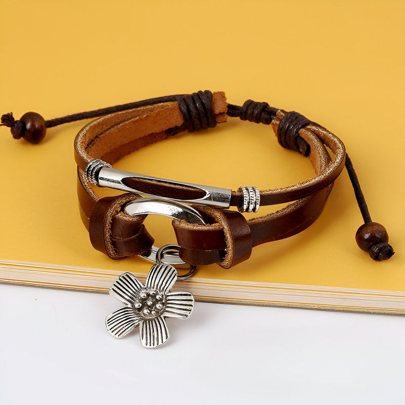 Bracelet multi-rangs en cuir marron avec charm fleur en métal argenté et cordon réglable.