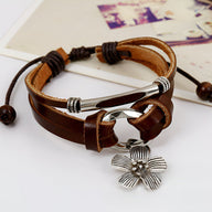 Bracelet multi-rangs en cuir marron avec fermoir argenté et charm fleur en métal finement détaillé.