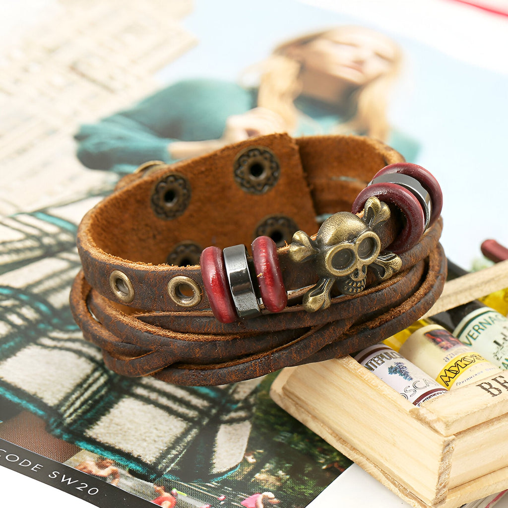 Bracelet multi-rangs en cuir marron avec motif tête de mort en métal et détails rouges.
