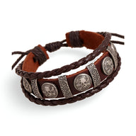 Bracelet multi-rangs en cuir marron avec têtes de mort métalliques et détails tressés.