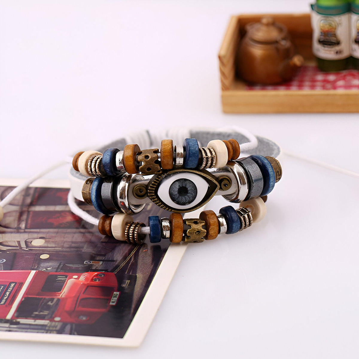 Bracelet multi-rangs en cuir blanc et bleu avec perles en bois et symbole œil de protection en métal.