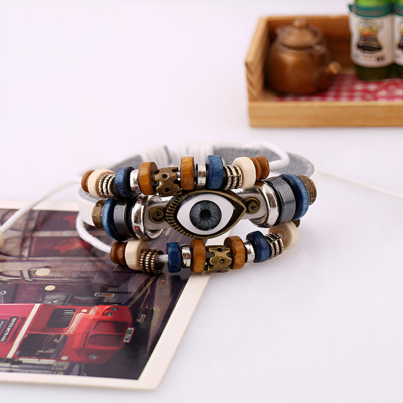 Bracelet multi-rangs en cuir blanc et bleu avec perles en bois et symbole œil de protection en métal.