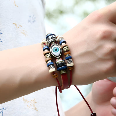 Bracelet multi-rangs en cuir rouge avec perles bleues, blanches, noires et œil de protection bleu au centre.