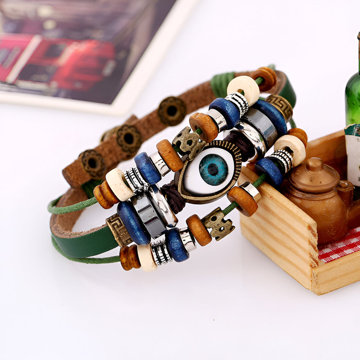 Bracelet multi-rangs en cuir vert avec perles blanches, marron, bleues et un pendentif œil de protection bleu vif.