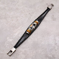 Bracelet multi-rangs en cuir noir avec motif tête de mort colorée et fermoir métallique argenté.